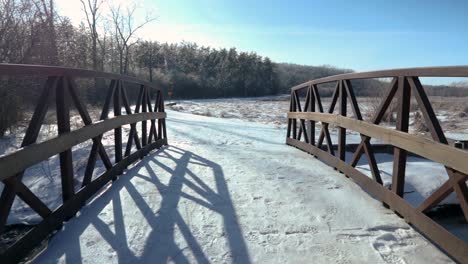 Crossing-a-beautifully-structured-small-wooden-bridge-on-a-forest-trail-in-an-urban-park