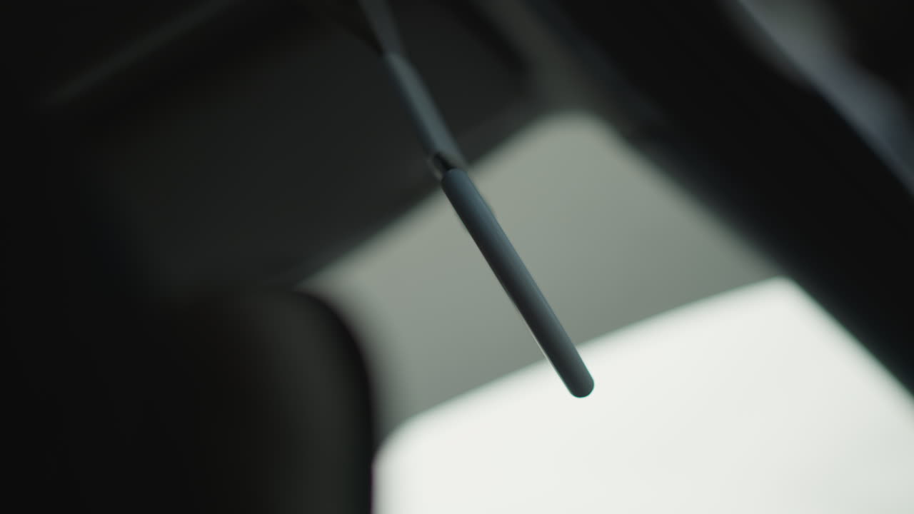 Side view inside moving car showing heart shaped handle swinging by passenger seat window with blurred urban background during winter commute capturing subtle motion and cabin detail