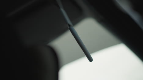 side view inside moving car showing heart shaped handle swinging by passenger seat window with blurred urban background during winter commute capturing subtle motion and cabin detail