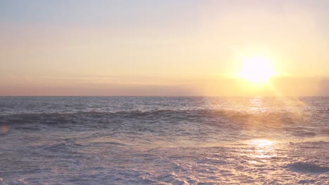 sunset over the ocean with waves crashing on the shore