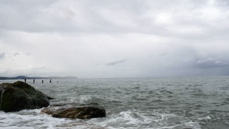 powerful splashing ocean tide waves breaking wild overcast coastal rocky shoreline closeup