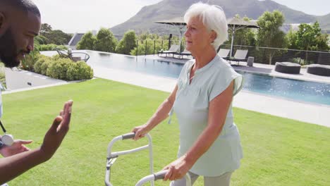 Video-of-happy-african-american-male-doctor-taking-care-of-caucasian-senior-woman-in-garden