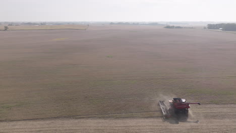 high-aerial side-view of combine harvester in expansive soybean field on hazy hot day