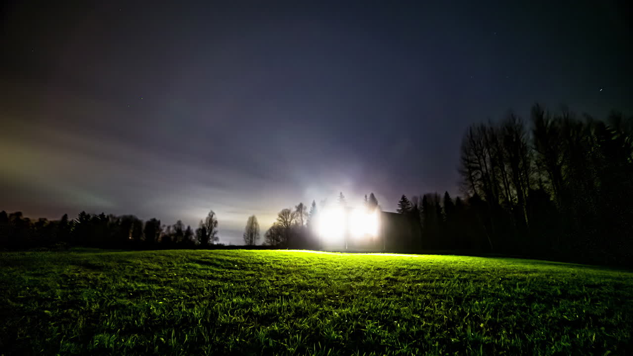 Time-lapse noturno incrível de um céu estrelado espetacular com uma luz mística no meio de um campo gramado