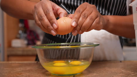 rompiendo huevos en un recipiente de vidrio para mezclarlos o agregarlos a una receta casera - vista lateral aislada