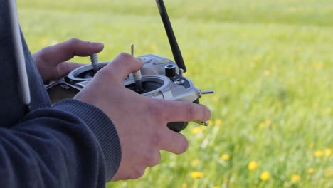 perfil lateral de manos caucásicas usando un control remoto de radio al aire libre en un campo