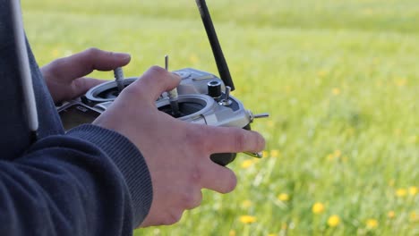 side profile of caucasian hands using a radio remote control outdoors in a field