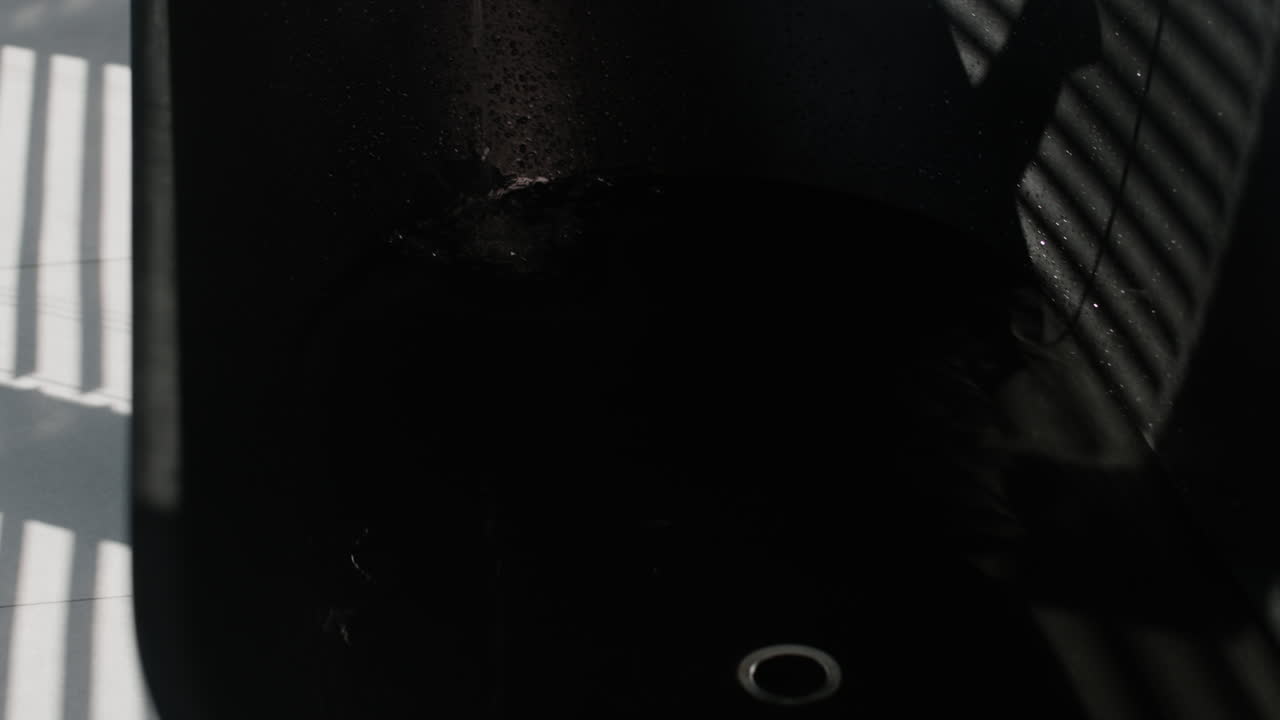 Empty dark sink with water drops and shadows