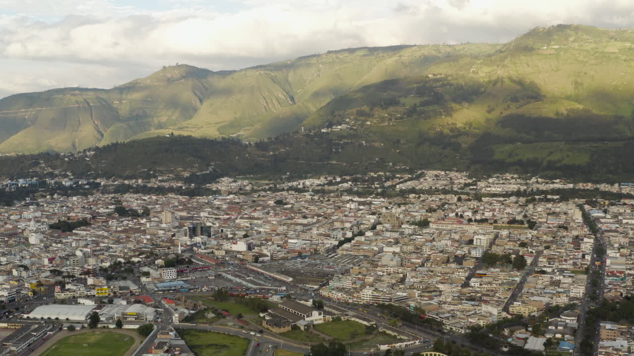 Aerial View of a City Nestled at the Base of Green Mountains
