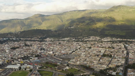 aerial view of a city nestled at the base of green mountains