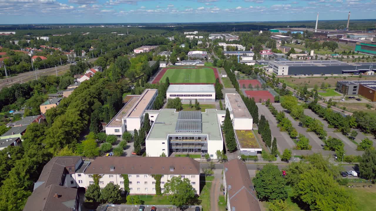 sports facilities at Hennigsdorf high school, including a soccer field, running track and other buildings in residential areas. Majestic aerial view flight static tripod hovering drone
