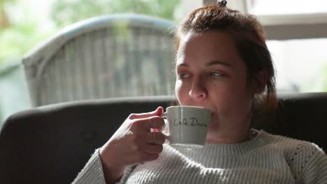 beautiful woman takes sip of steaming hot cup of coffee in small white cup