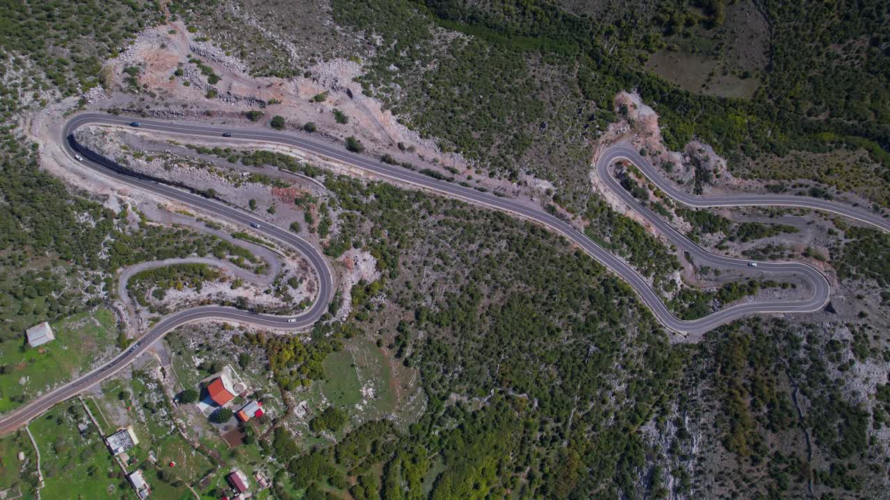 sinuoso camino de montaña en el lado rocoso de las montañas alpinas cerca de un pueblo turístico en albania