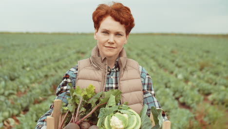 portrait of female farmer with crate of fresh vegetables