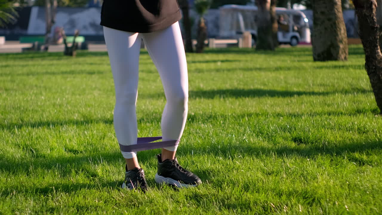 공원 에서 저항 밴드 와 함께 운동 하는 여자