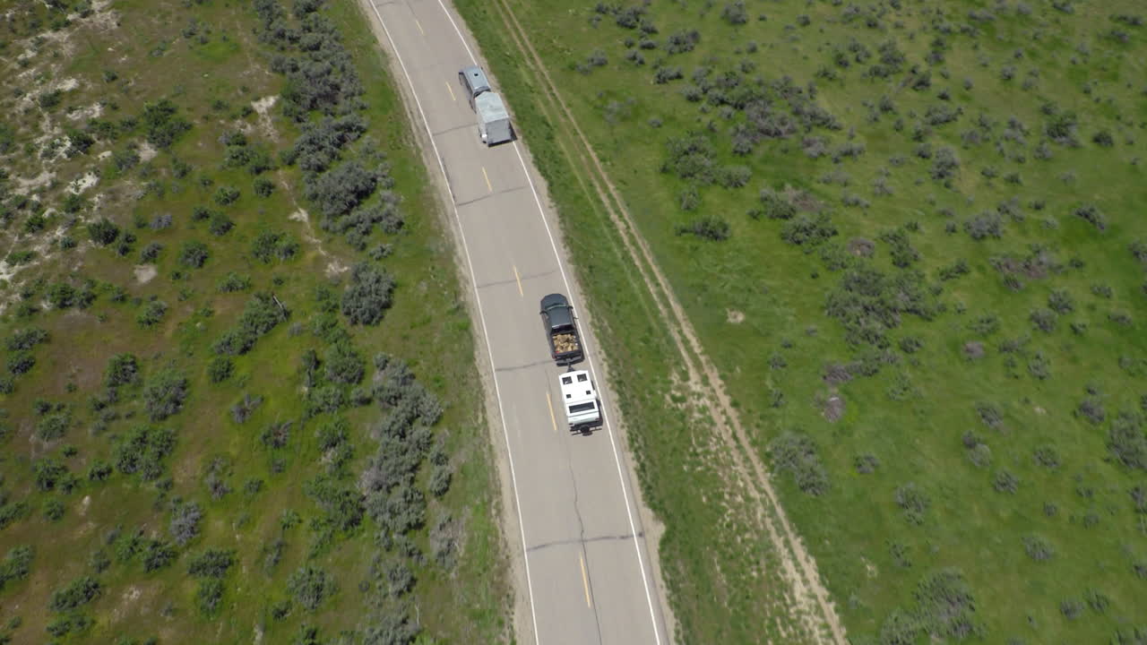 antena escénica persiguiendo a dos vehículos con remolques recreativos conduciendo en el medio oeste de estados unidos, carreteras de colorado