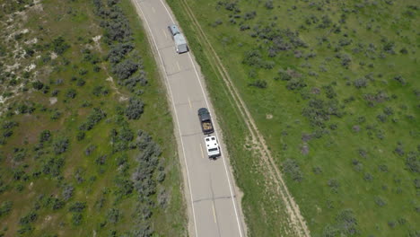 Antena-Escénica-Persiguiendo-A-Dos-Vehículos-Con-Remolques-Recreativos-Conduciendo-En-El-Medio-Oeste-De-Estados-Unidos,-Carreteras-De-Colorado