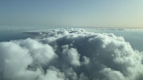 aerial view from a cockpit overflying few clouds with afternoon light over the sea