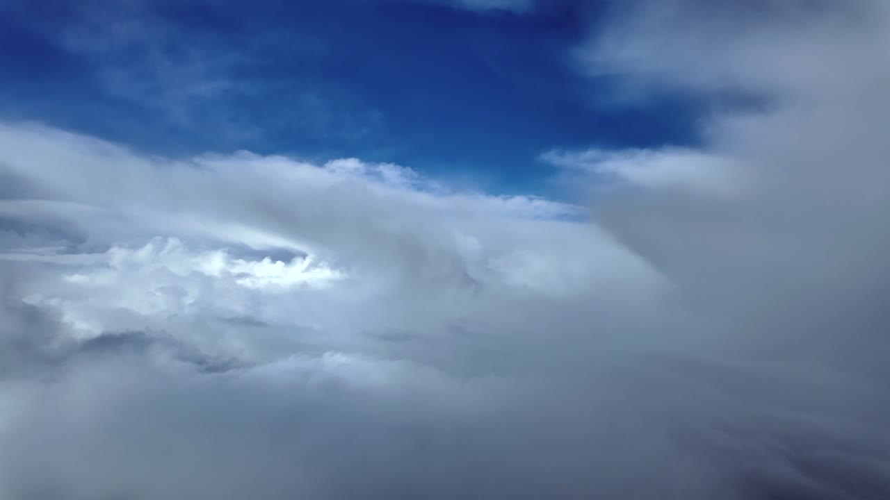 Immersive pilot’s eye POV view captured from a jet airplane cockpit while flying through broken clouds with patches of deep blue sky above