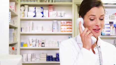 Pharmacist-holding-prescription-paper-while-talking-on-phone