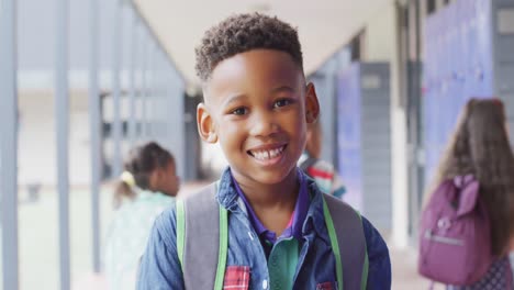 Porträt-Eines-Glücklichen-Afroamerikanischen-Schuljungen,-Der-Im-Schulkorridor-Spaziert