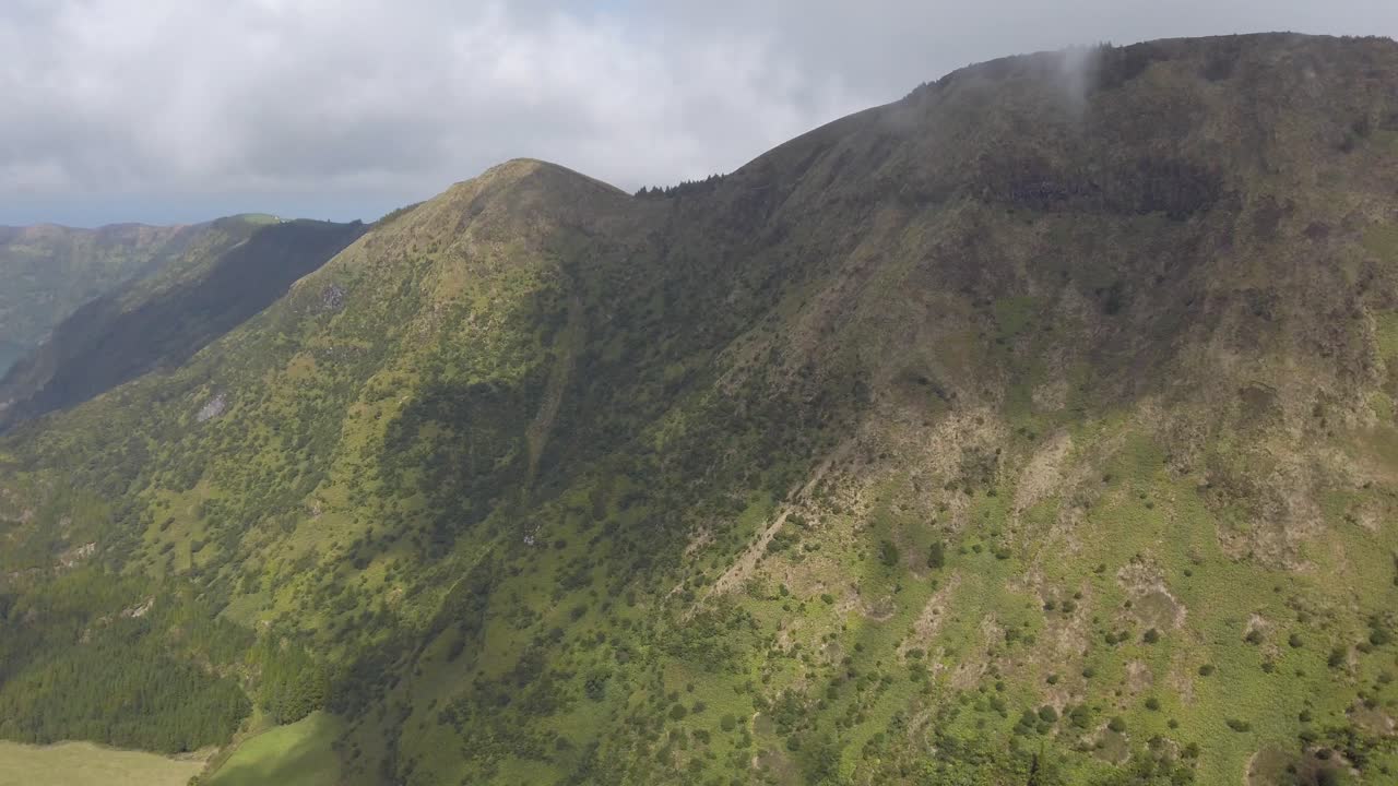 Gimbal pan of girl walking toward peak of Miradouro da Boca do Inferno, Sao Miguel, Portugal