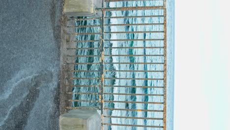 Eroded-coastal-fence-with-ocean-horizon,-vertical-view