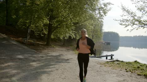 runner running on lakeside near woods on sunny day