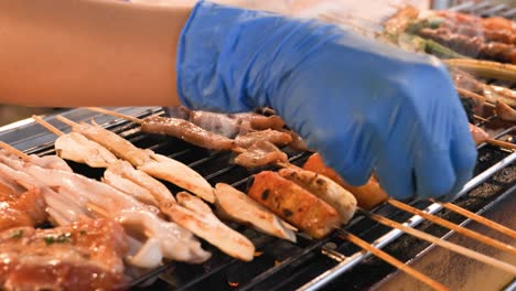 a street vendor is grilling assorted bbq meat and vegetable on bamboo skewers with sauce