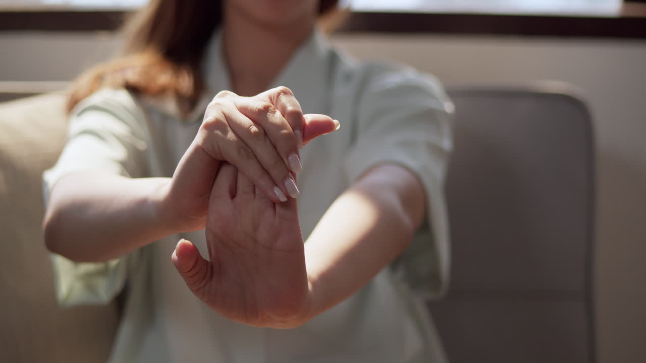 Close-up shot of a woman's hands as she gently massages and stretches each of her fingers.