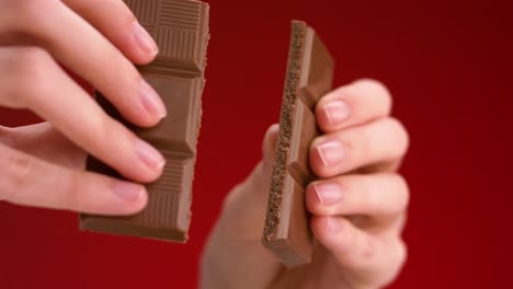 las manos de una mujer rompiendo una barra de chocolate