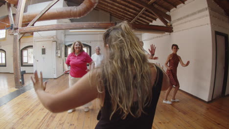 back view of female teacher learning moves with senior people