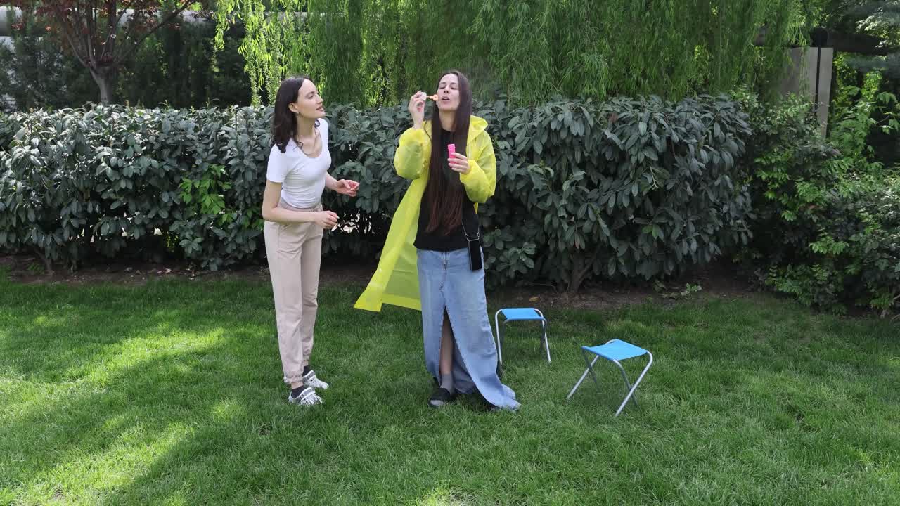 Two women playing with bubbles in a garden