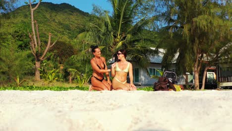 attractive young women fixing hair on quiet exotic beach sitting on white sand with palm trees background in philippines