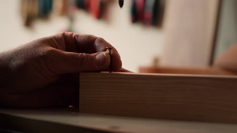 carpenter sinks screws into wooden surfaces with power drill, close up