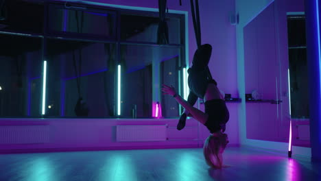 la mujer está entrenando en una clase de yoga aérea balanceándose en una hamaca por encima del piso de fitness y ejercicio físico