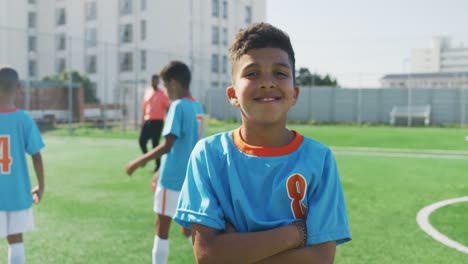 Mixed-race-soccer-kid-in-blue-smiling-and-looking-at-camera