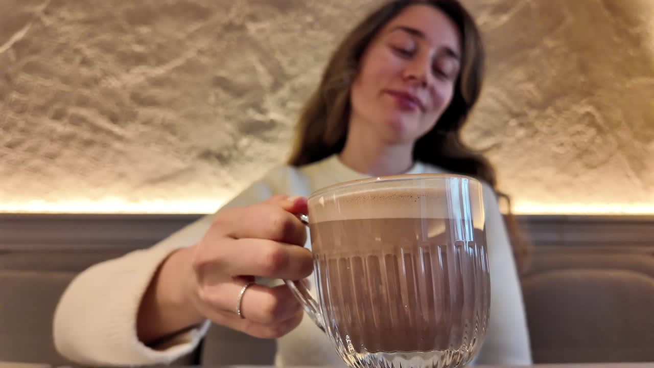Brunette, young woman drinking coffee with a biscuit at a cafe