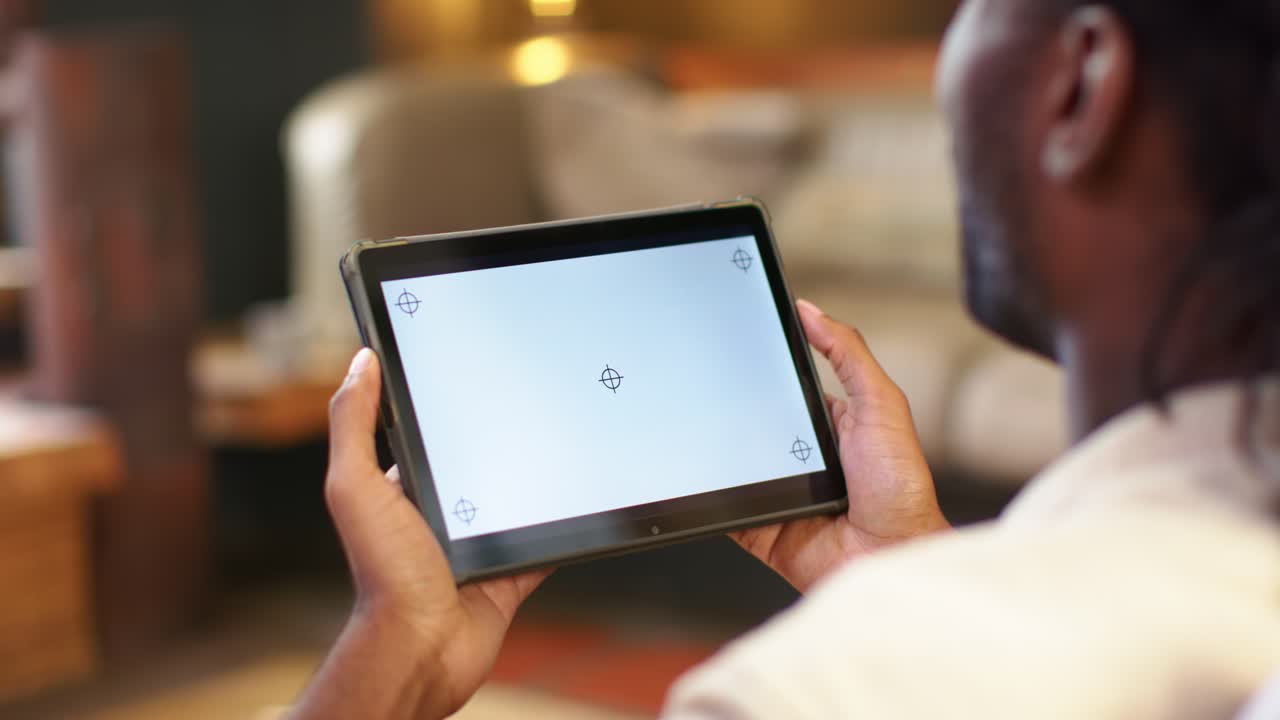 Dospělý africký muž drží tablet s nitkovými kříži, upravuje úchop při kalibraci doma