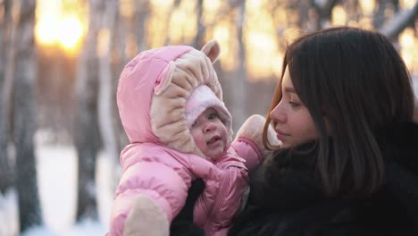 mother and baby in a snowy forest at sunset