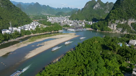 aerial tilt shot of ferries in front of the xingping ancient town, summer in china