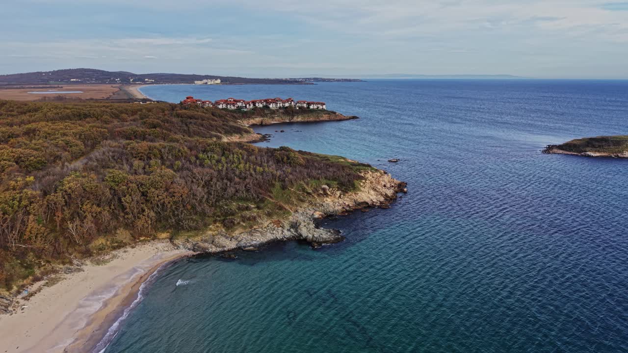 Coastal view of sandy beach and rocky shore under clear blue sky