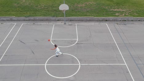 a man playing basketball on an empty basketball field and trying to throw the basketball into the basketball ring