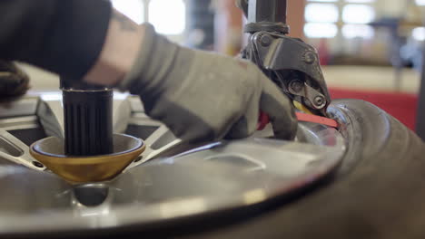 técnico de neumáticos en el taller utiliza una máquina para quitar el neumático de la llanta, primer plano