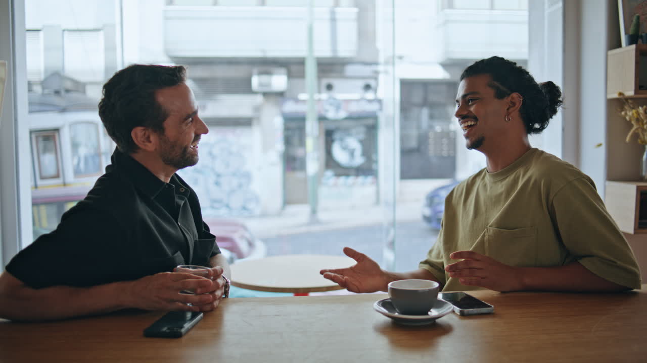 Laughing men friends enjoy weekend meeting in small restaurant close up.