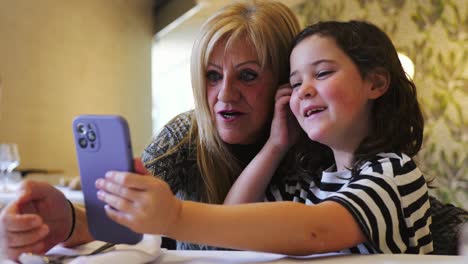 positive woman and girl taking selfie on smartphone