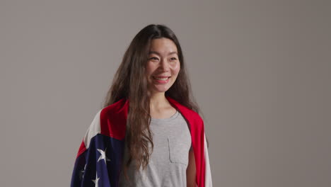 close up studio shot of woman wrapped in american flag celebrating 4th july independence day 2