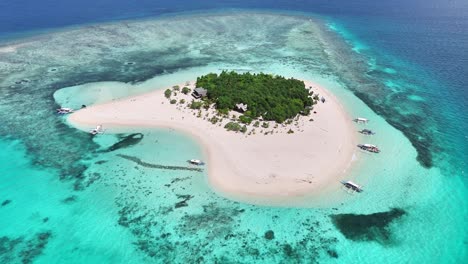 drone glides toward the heart-shaped patawan island, revealing white sand beaches, lush vegetation, and coral-rich waters in the sulu sea, near southern palawan, balabac, philippines