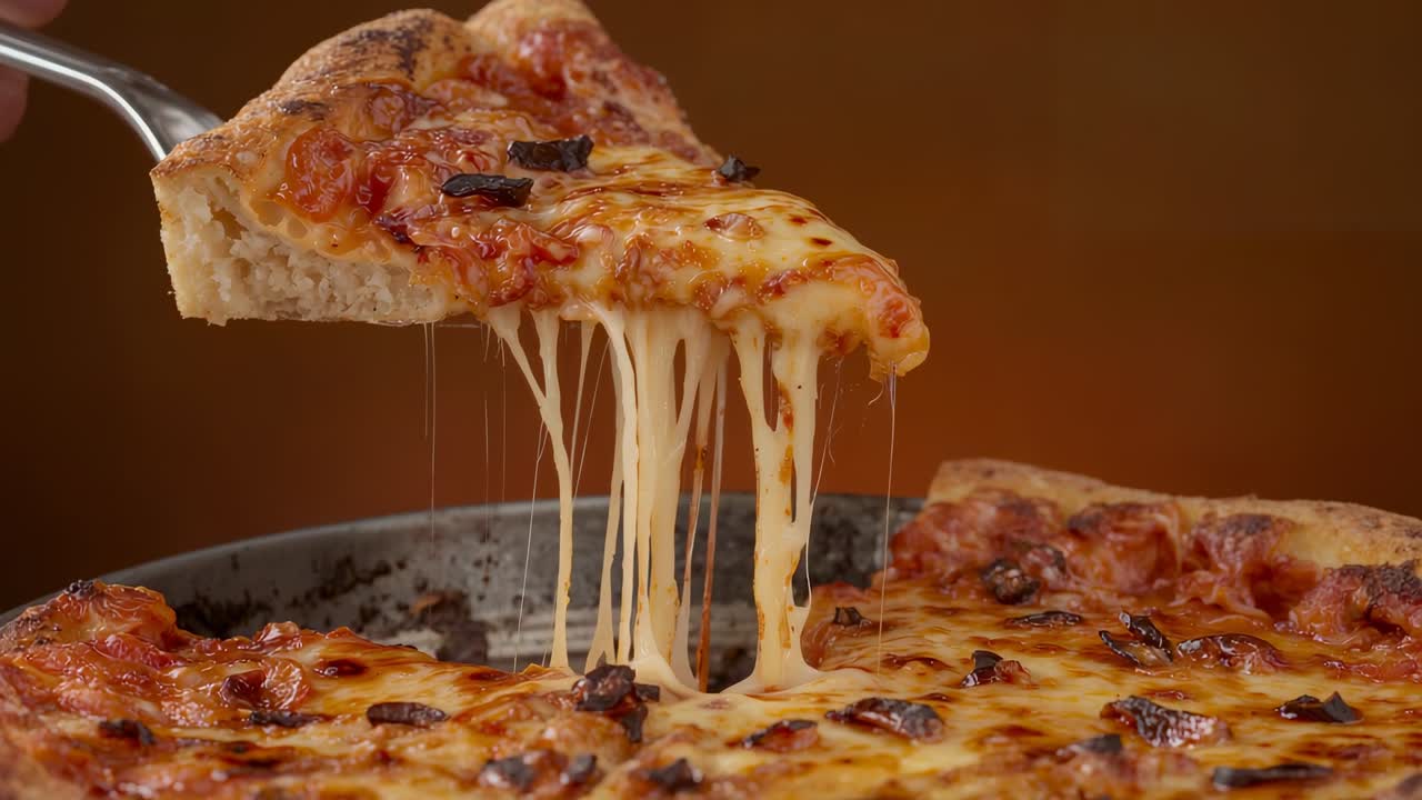 Spatola che scivola sotto una fetta di pizza sul tavolo, mano che solleva la fetta dalla teglia mostrando i fili di formaggio