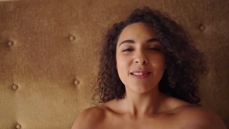 a beautiful woman with curly hair smiles directly at the camera